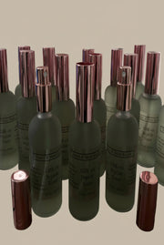 Set of green perfume bottles with rose gold caps on a wooden surface.